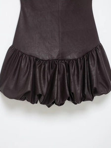 Détail de l'ourlet bouffant volumineux sur cette robe en similicuir foncé