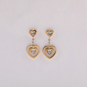Detail of gold heart earrings featuring hollow pendants and clear zircon stone settings