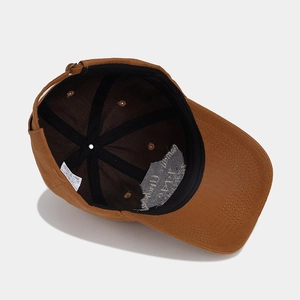 Internal view of brown cotton baseball cap showing six-panel structure and metal buckle