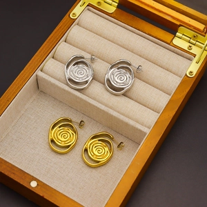 Abstract spiral vortex stud earrings in gold and silver finish on linen jewelry box