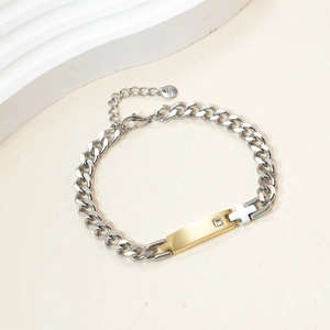 Cuban chain bracelet with golden nameplate, zircon stone, and cross on white background