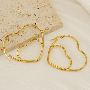 Gold double-layered hollow heart earrings on beige stone and white pleated fabric
