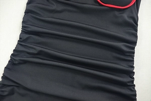Détail de la robe en tissu plissé noir avec bordures passepoilées rouges contrastées