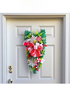 Detail of Christmas candy cane teardrop wreath with red bows and snowflakes on white door