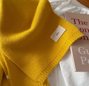 Detail of yellow knit scarf with emo label, soft wool texture for winter warmth