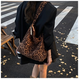 Chic leopard print hobo bag with wooden bead charm shown in a street style setting