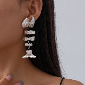 Detailed close-up of a silver-tone fishbone earring showing movable metal segments and texture