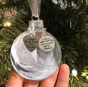 Detailed close-up of a 6cm clear memorial ornament with white feathers and heart charm