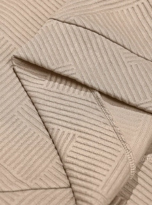 Macro shot of khaki ribbed knit fabric showing detailed texture and stitching of the hoodie