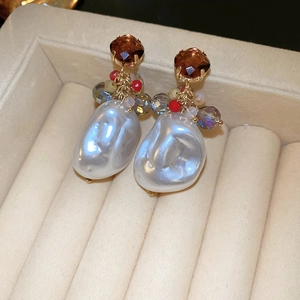 Close-up of vintage gold earrings with brown gems, colorful beads and baroque pearls