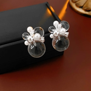 Macro shot of silver needle earrings with transparent globes and pearls on a black box