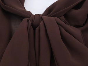 Dettaglio del fiocco su un abito in chiffon marrone scuro con trama del tessuto fine