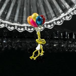 Détail macro d'une broche grenouille émaillée avec ballons colorés sur verre