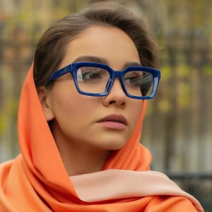 Chic blue thick square frame glasses worn by a model in a high-fashion outdoor setting