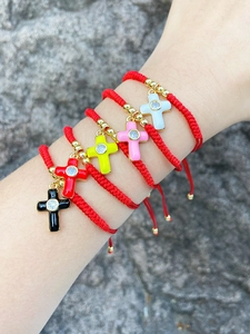 Close-up of adjustable red cord bracelets with colorful enamel cross pendants and zircons
