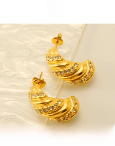 Détail de boucles d'oreilles croissant en or 18k avec zircon incrusté et texture spirale