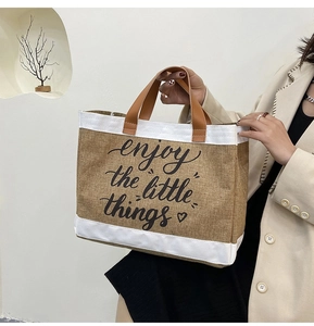 Detail of jute tote bag showing leather handles and enjoy the little things print