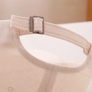 Close-up of adjustable metal buckle and twill cotton fabric on beige kids baseball cap