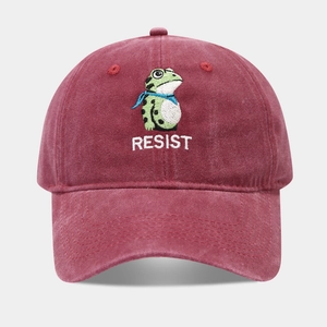 Detail of burgundy washed cotton baseball cap featuring green frog and RESIST embroidery