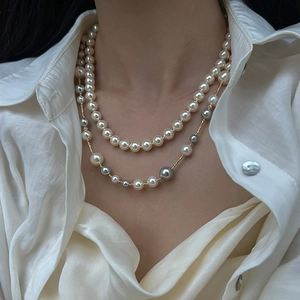 Elegant layered necklace with white and grey pearls on high-gloss gold chain design