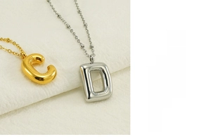 Macro detail of 3D bubble letter C and D charms on gold and silver beaded chains