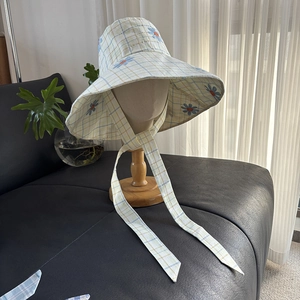 Detail of checkered sun hat with blue daisy embroidery and adjustable chin straps