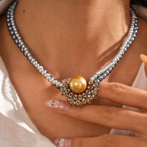 Dettaglio della collana di perle a doppio strato con ciondolo a girasole su modella