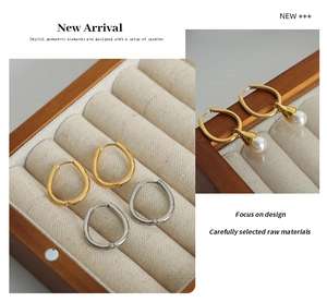 Detail of gold and silver U-shaped hoop earrings with white pearl drop in jewelry box