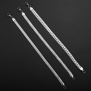 Set of three silver stainless steel Cuban link necklaces in varying lengths on black background
