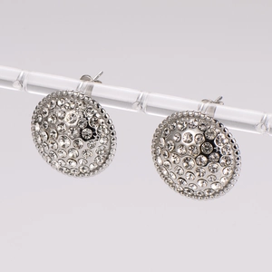 French style round silver earrings with pave set crystals on a transparent stand