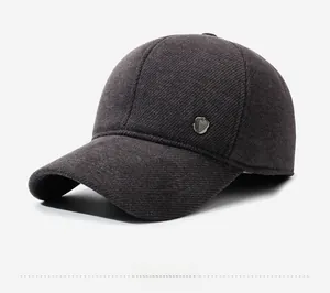Detail der dunkelgrauen Twill-Struktur und Metallemblem auf der Winter-Baseballkappe