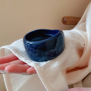 Detail of a deep blue wide resin bangle with a polished finish worn on the wrist
