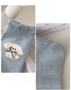 Detail of sky blue kids socks showing ruffled cuffs, 3D puppy embroidery and bows