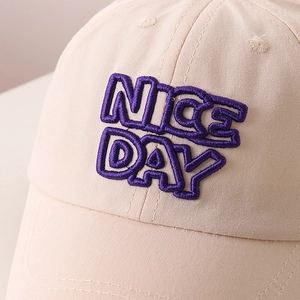Gros plan détaillé de la broderie violette 3D 'NICE DAY' sur une casquette en coton beige