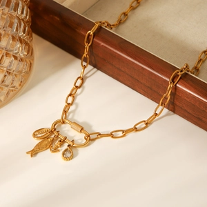 Détail d'un collier nautique doré avec pendentifs poisson et ancre sur une boîte en bois