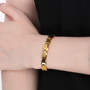 Close-up of a polished gold-plated magnetic tungsten steel bracelet worn on a male wrist