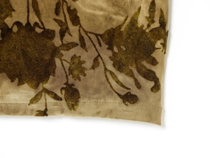 Macro detail of flocked velvet floral pattern and stitched hem on a pleated dress