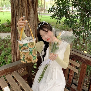 Sunflower print fabric mini tote bag with yellow handle and white ruffle detail in park