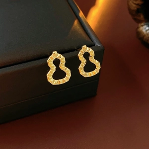 Macro detail of golden gourd-shaped stud earrings with faceted metallic texture