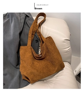Detailed texture of brown corduroy tote bag displayed on a stylish beige sofa