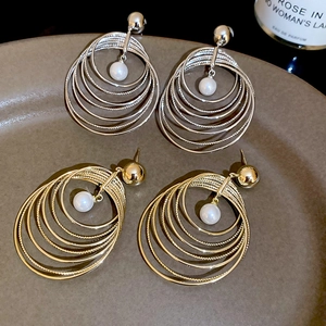 Detail of multi-layered round gold and silver earrings with white center pearls