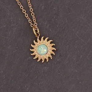 Detail of golden sunflower pendant with light green gemstone and classic metal chain
