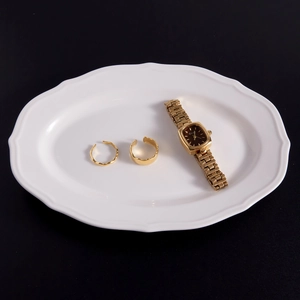 Macro shot of 18k gold plated stainless steel watch and assorted rings on white tray