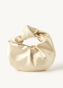 Detailed close-up of knotted handle and pleated satin texture on light gold evening bag