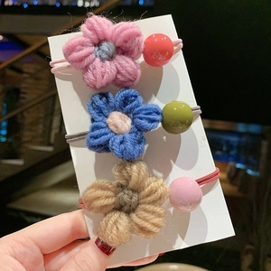 Dettaglio di tre elastici per capelli con fiori fatti a mano e perline colorate