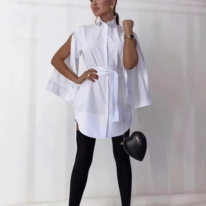 Detail of elegant white shirt dress showing deep sleeve slits and tied waist belt design