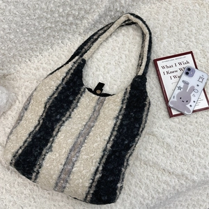 Close-up of plush striped tote bag featuring fleece texture and black snap button closure