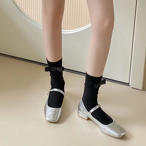 Detail of silver Mary Jane shoes styled with black socks featuring a sweet ribbon bow