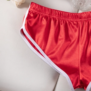 Dettaglio ravvicinato di pantaloncini da yoga in raso rosso con bordino bianco ed elastico