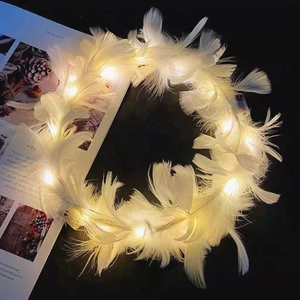 Macro shot of luminous white feather headband with warm yellow LED lights on dark backdrop